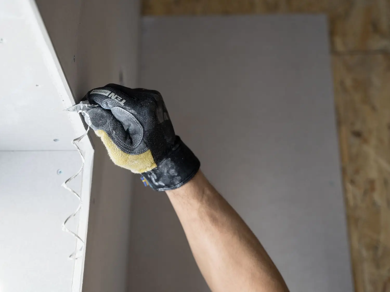 Gloved hand finishing a plaster corner with a knife